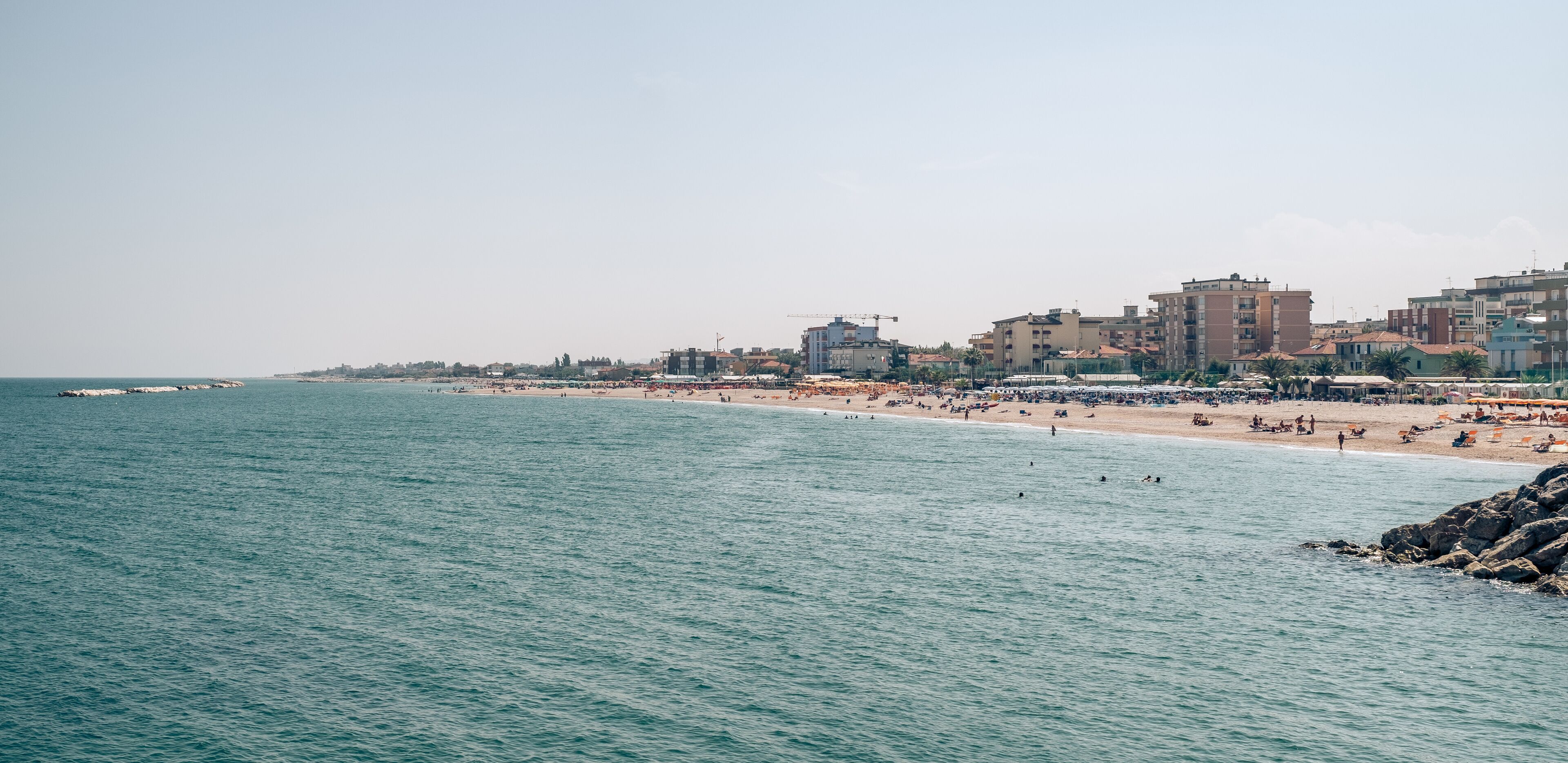 Un paisaje urbano costero con playa, edificios y un mar tranquilo.