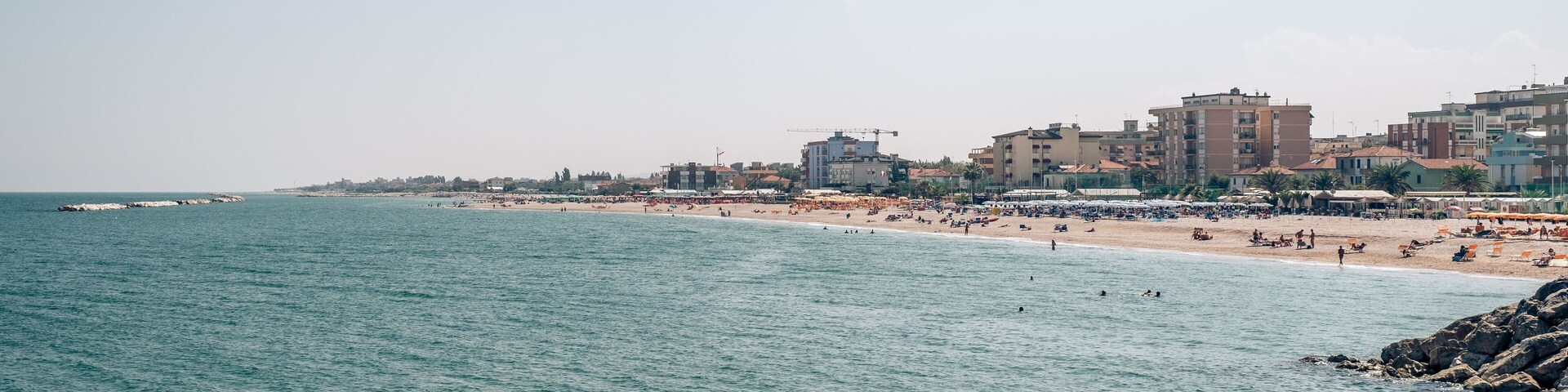 Un paisaje urbano costero con playa, edificios y un mar tranquilo.