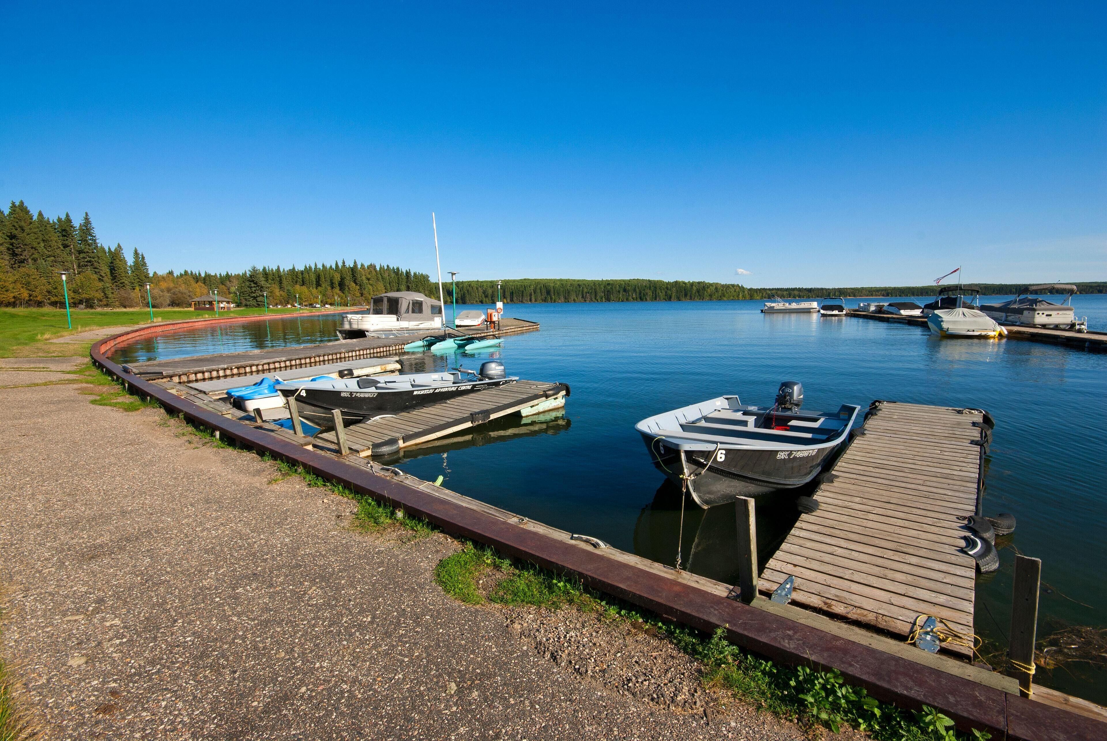 A calm lake with boats docked at a wooden pier.