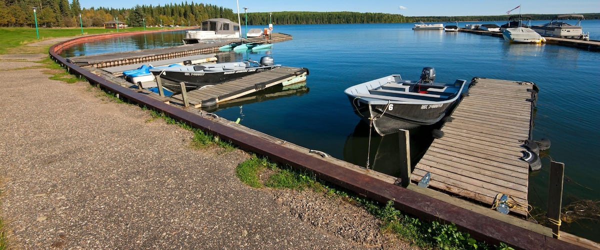 A calm lake with boats docked at a wooden pier.