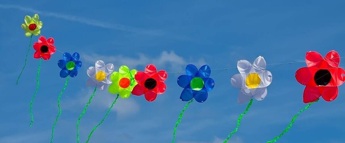 A string of colorful pinwheels against a clear blue sky.