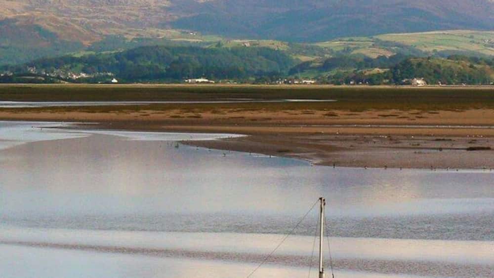 A boat on a calm lake with mountains in the background.