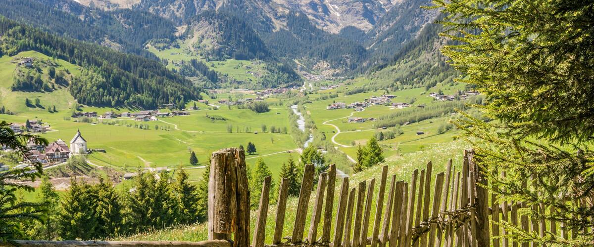 A mountainous landscape with a winding river, green fields, and scattered houses.