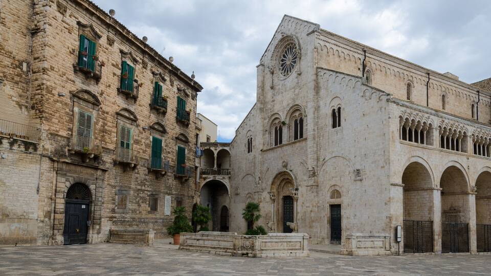 A historic stone building with green shutters and a large arched entrance.