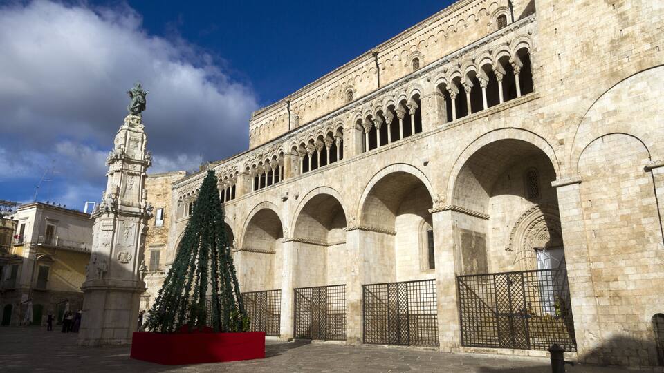 A historic building with arches and a statue.