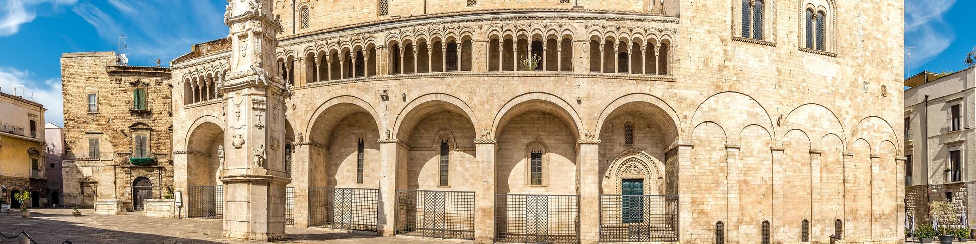 A historic building with a central courtyard, arched walkways, and a prominent clock tower.