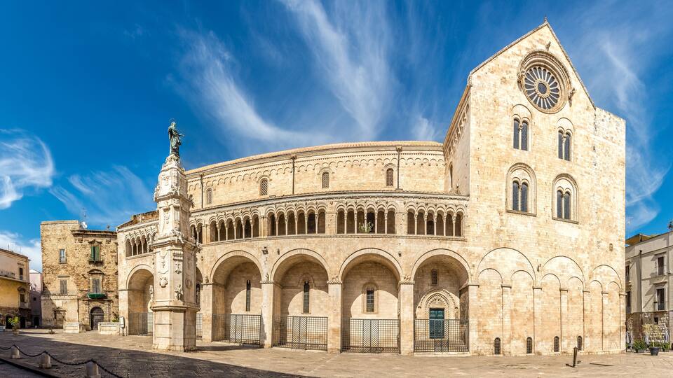 A historic building with a central courtyard, arched walkways, and a prominent clock tower.