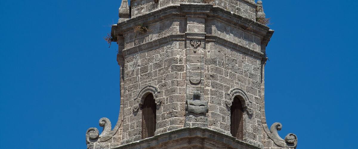 A tower with a yellow and green dome and a weather vane.