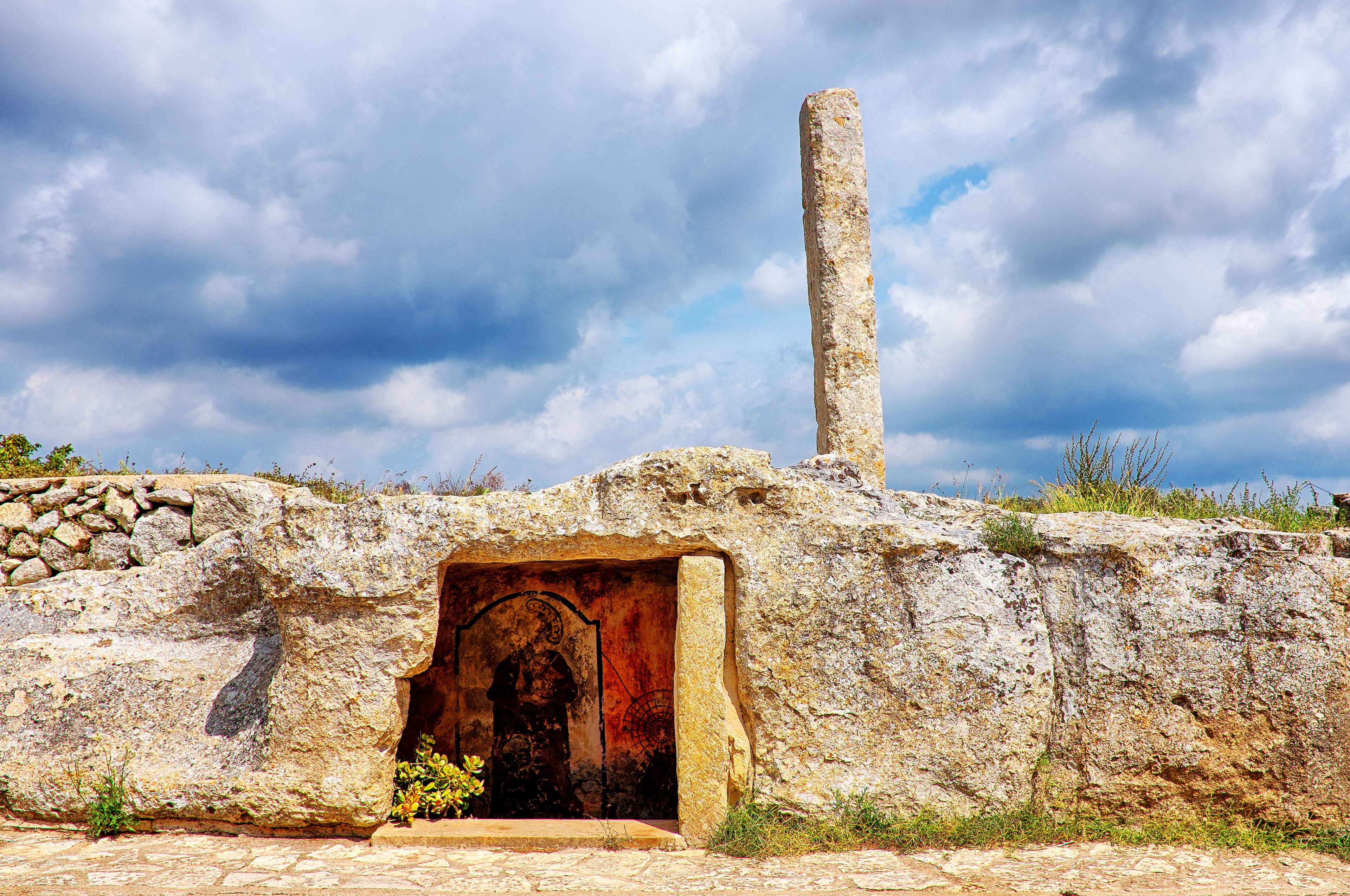 An ancient stone structure with a large doorway and a tall pillar.