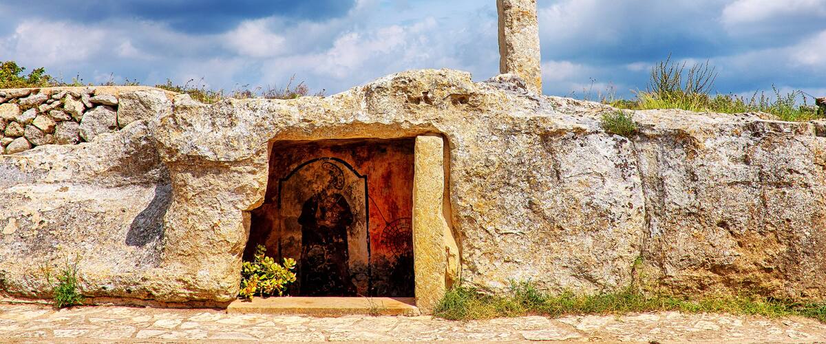 An ancient stone structure with a large doorway and a tall pillar.