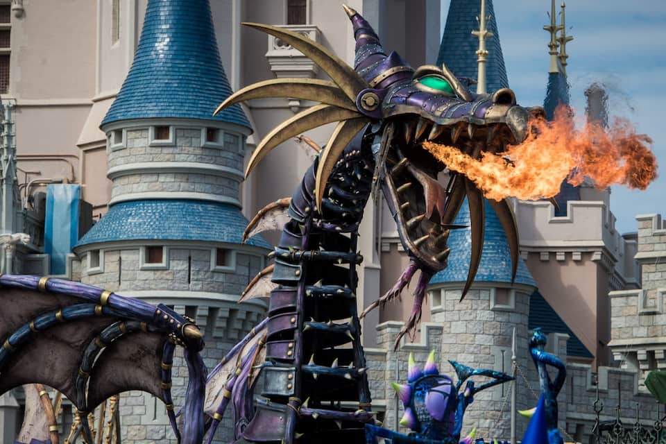 Um dragão com uma gema verde e um castelo azul ao fundo.