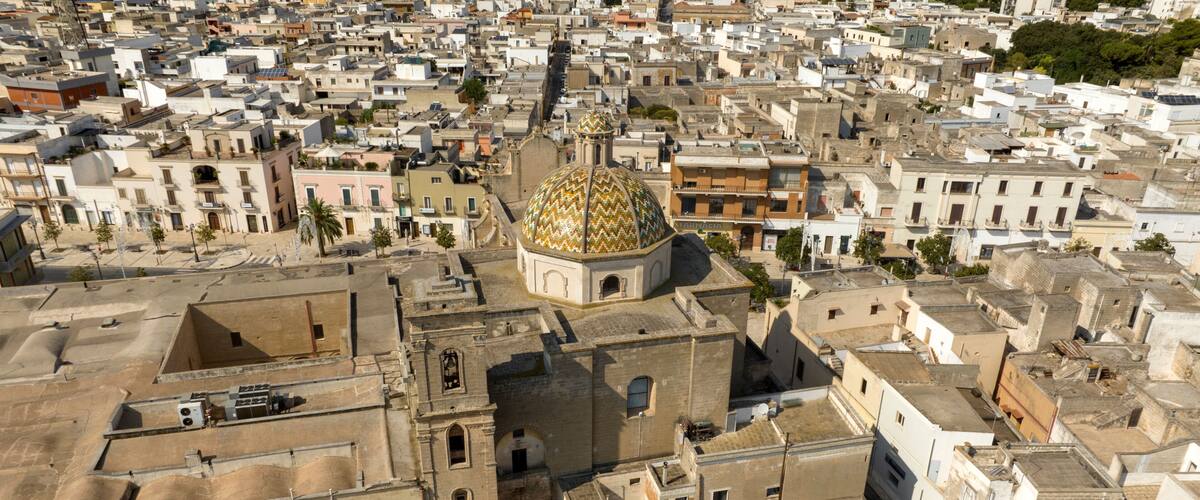 Une zone urbaine densément peuplée, caractérisée par un bâtiment imposant surmonté d’un dôme doré, des rues étroites et une architecture traditionnelle.