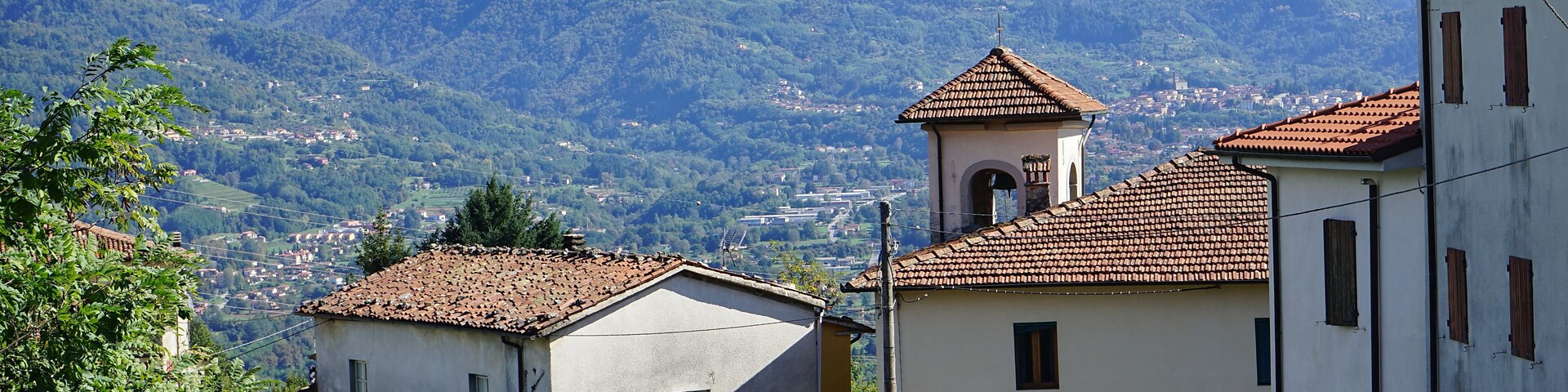 Un paisaje montañoso con un pueblo, una iglesia y un campanario, y casas escalonadas.