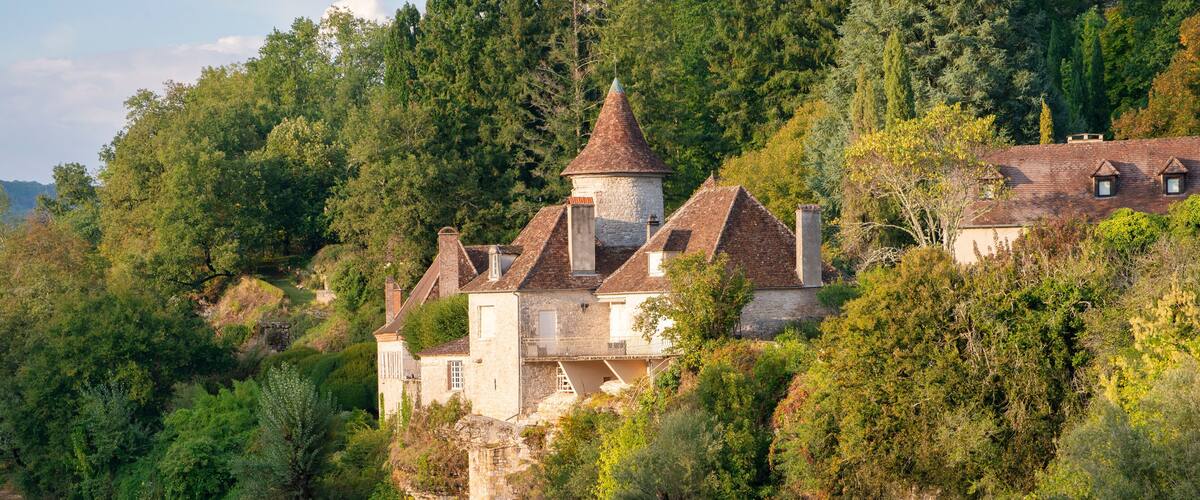 A castle on a hill overlooking a calm river.