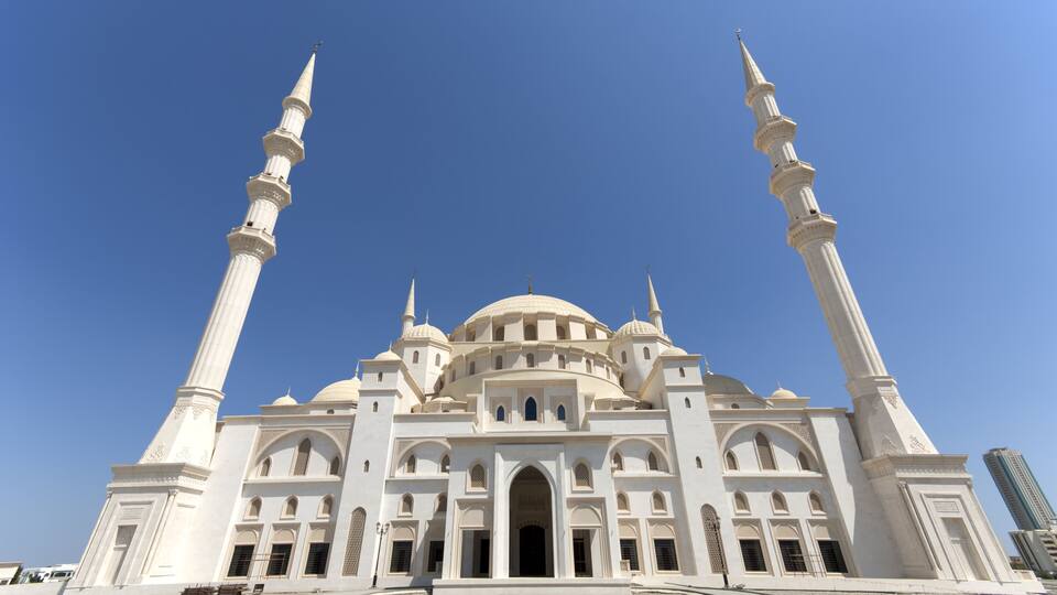 A large white mosque with multiple domes and minarets.