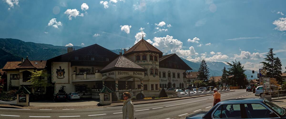 A town with a prominent building labeled "Hotel Rossl" and a mountain in the background.