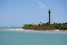 A coastal scene with a lighthouse, beach, and ocean.
