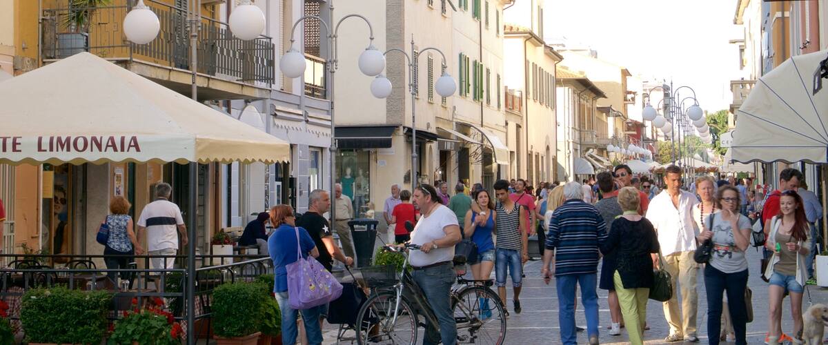 A crowded street with people walking, a bicycle, and a shop named "TE LIMONAIA".