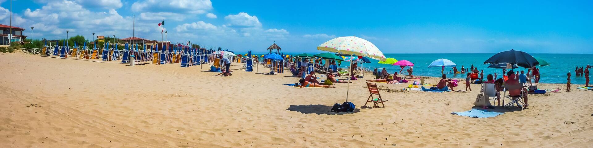 Beautiful vacation beach with beach chairs and sun shades on a sunny day at Lido di Metaponto, Basilicata, Italy