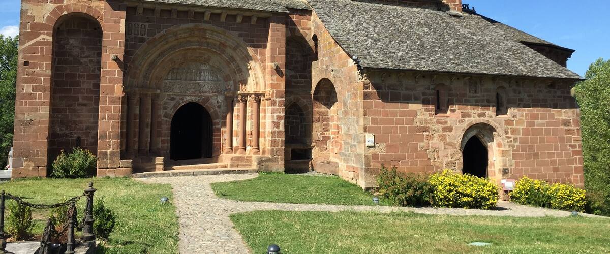 A historic stone church with a prominent entrance, a bell tower, and a well-maintained lawn.