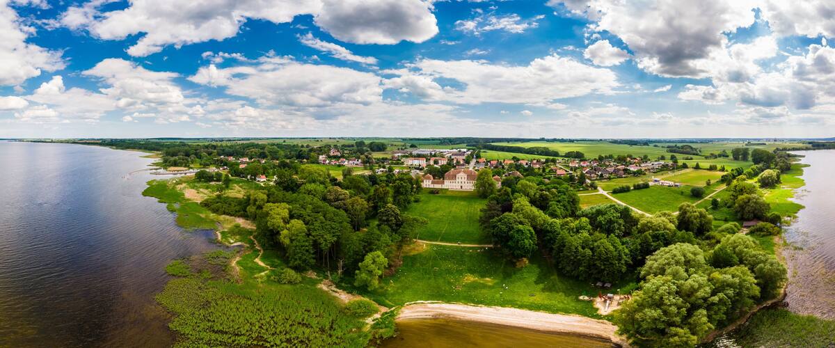 A lakeside town with a prominent castle, surrounded by lush greenery and fields.