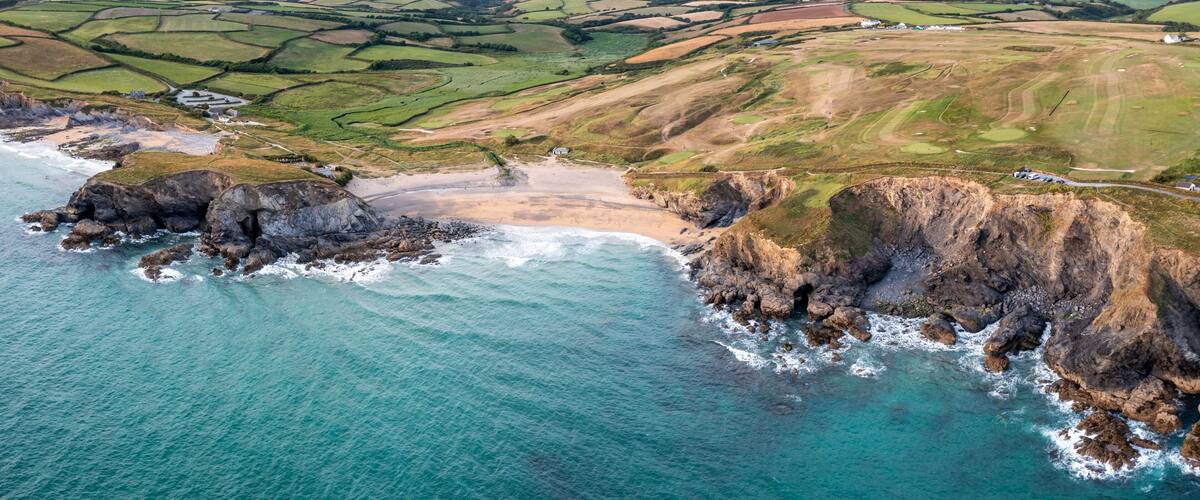 A coastal landscape with cliffs, a beach, and agricultural fields.