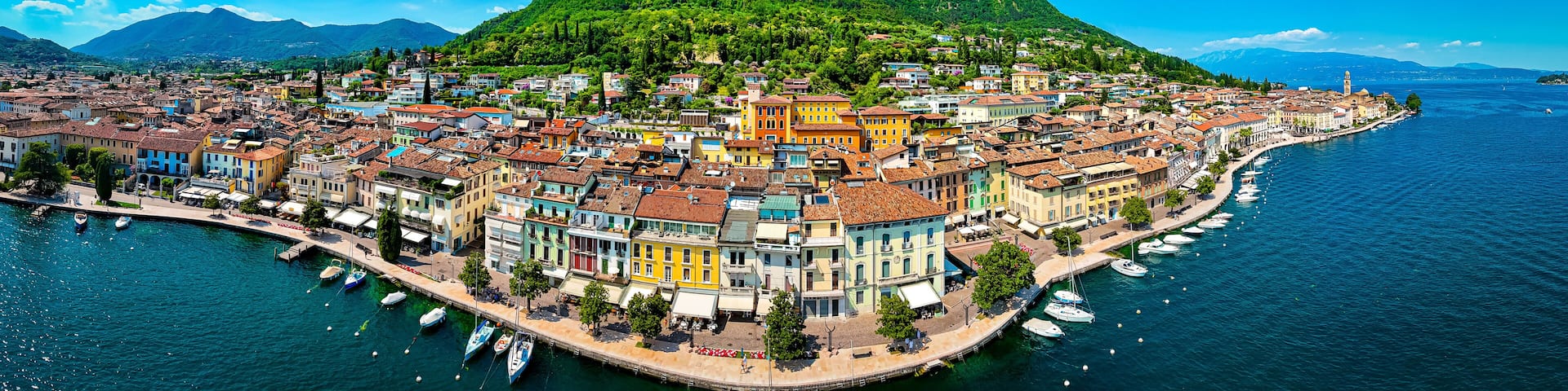 A coastal town with colorful buildings, a marina, and a mountain in the background.