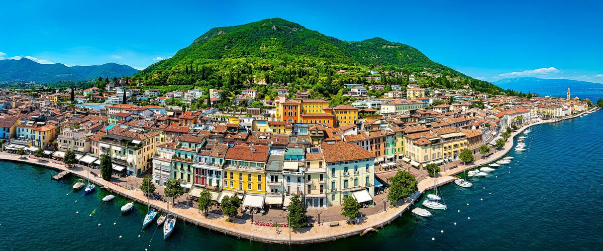 A coastal town with colorful buildings, a marina, and a mountain in the background.