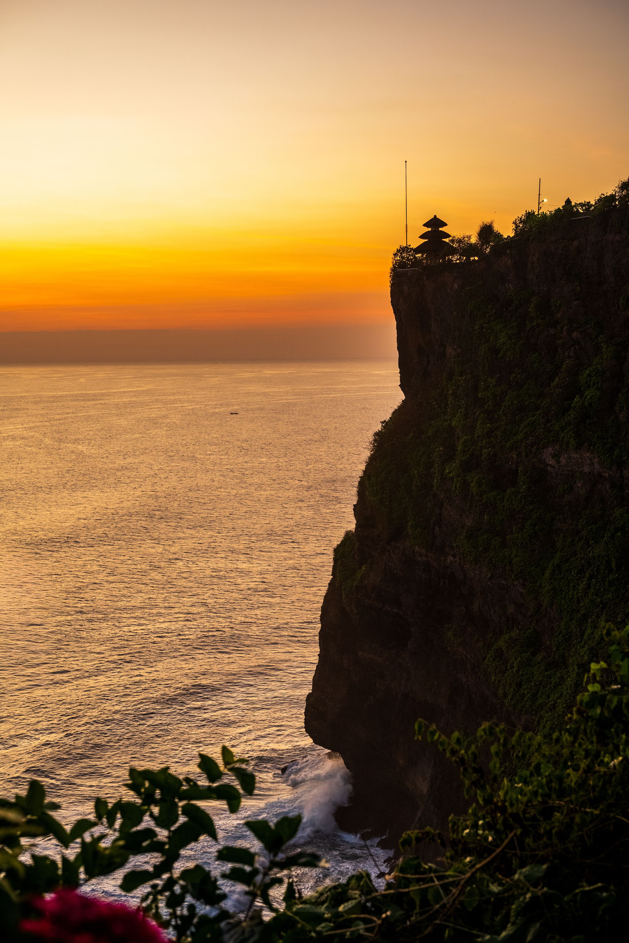 Uluwatu Temple stands on a dramatic cliff edge at sunset in Bali