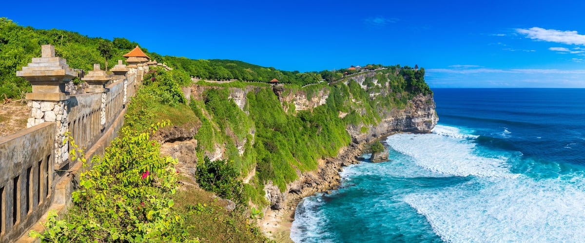 A coastal cliff with a stone wall and traditional buildings.