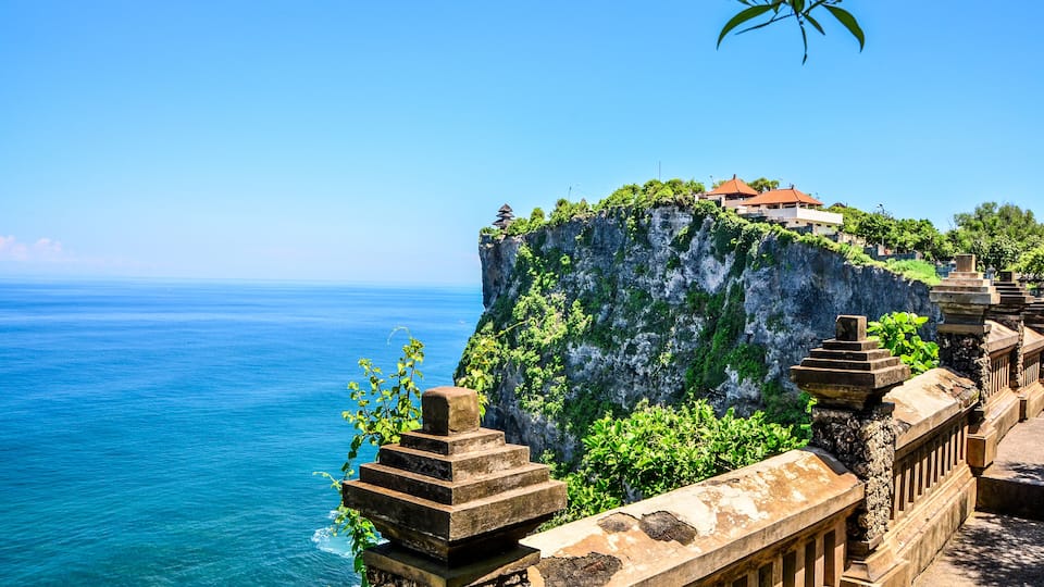 A coastal cliff with a traditional house perched on top, overlooking the sea.