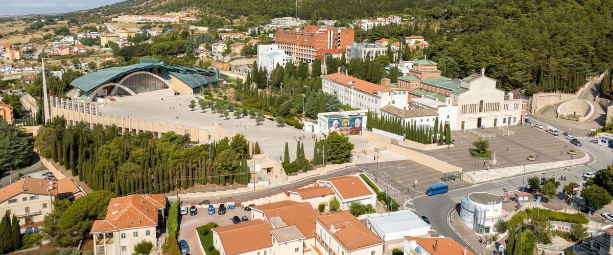 A town with a large stadium, historic buildings, and a hilly backdrop.