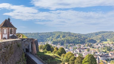 A historic stone wall, a church with a bell tower, and a town in the valley below.