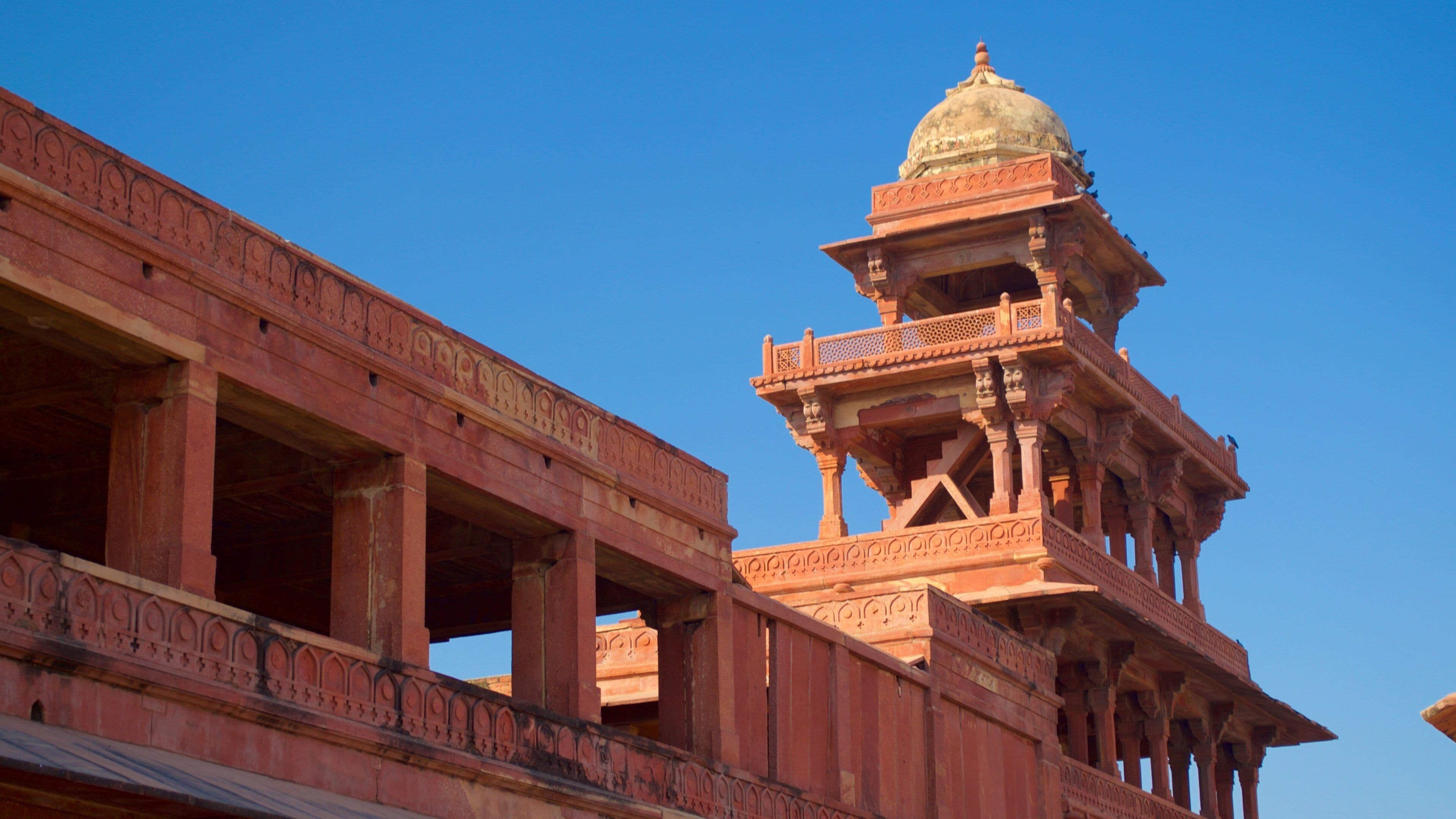 A red sandstone structure with intricate carvings and a dome.