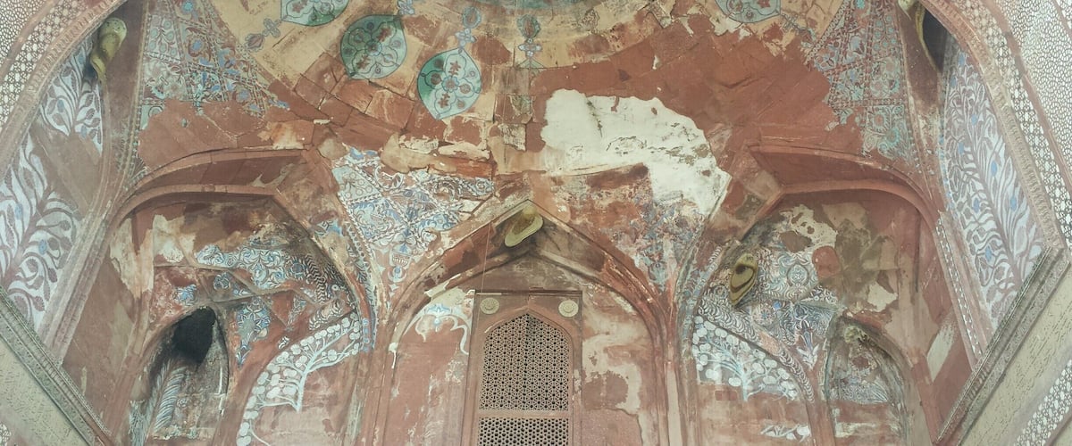 A weathered interior with intricate tile work and a central arched doorway.