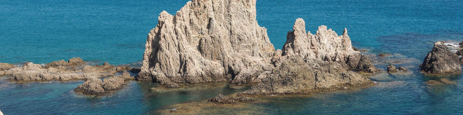 A rocky coastline with clear blue waters and prominent limestone formations.