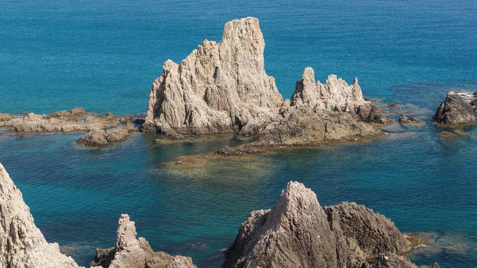 A rocky coastline with clear blue waters and prominent limestone formations.