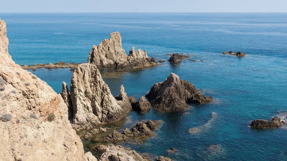 A rocky coastline with clear blue waters and rugged cliffs.