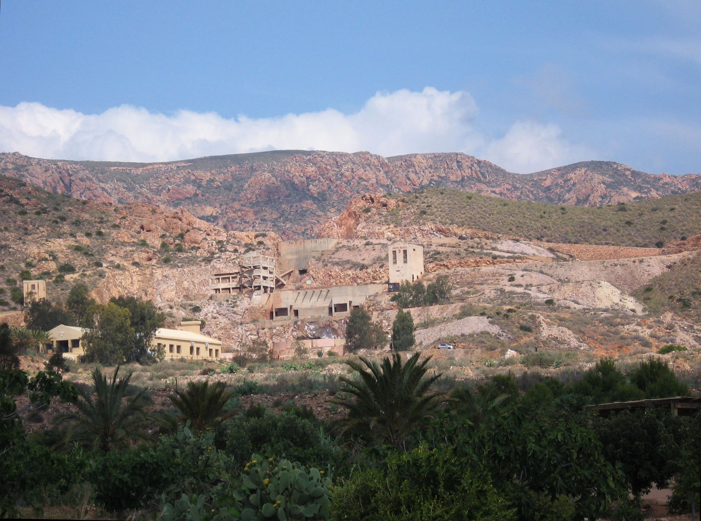 A rugged mountainous landscape with a small village and several buildings, including a church, nestled among rocky terrain and sparse vegetation.