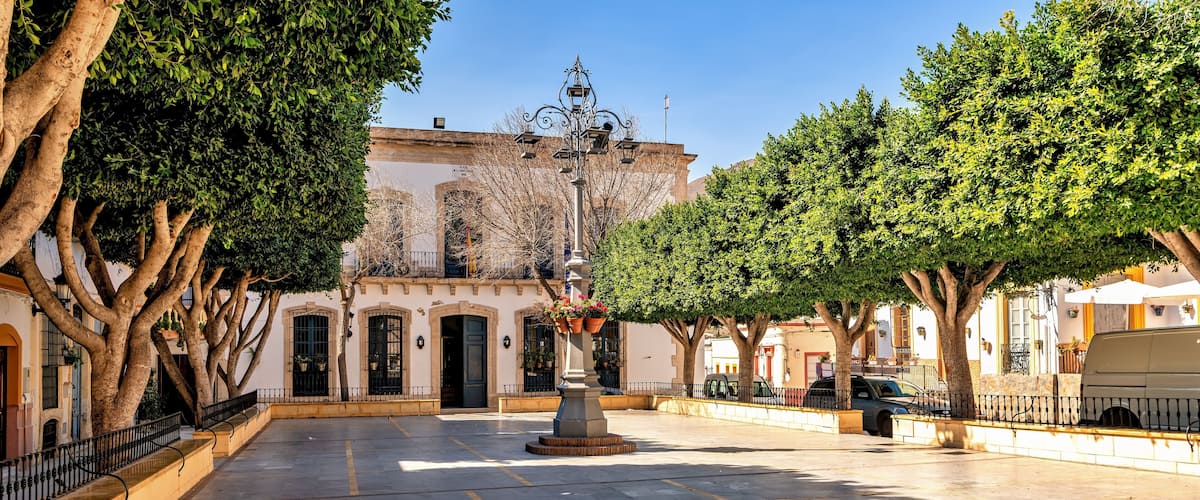 A plaza with a fountain, trees, and historic buildings.