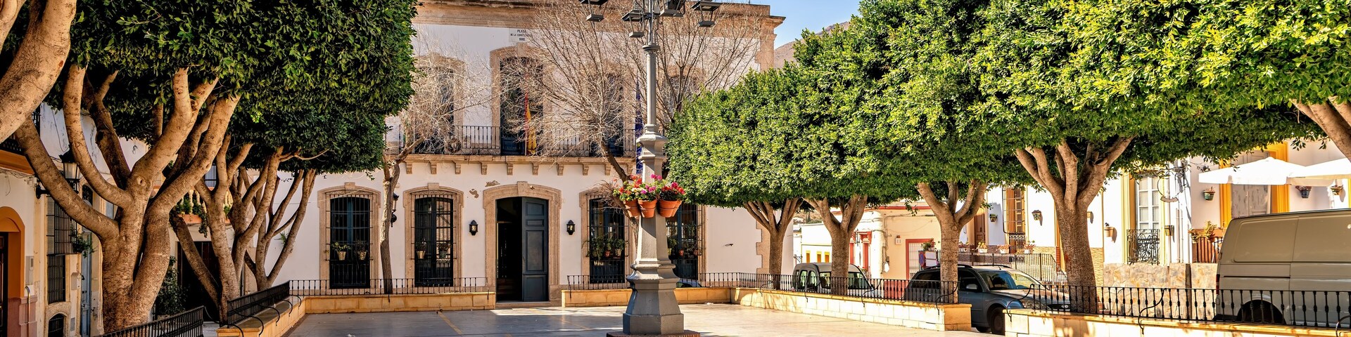 A plaza with a fountain, trees, and historic buildings.