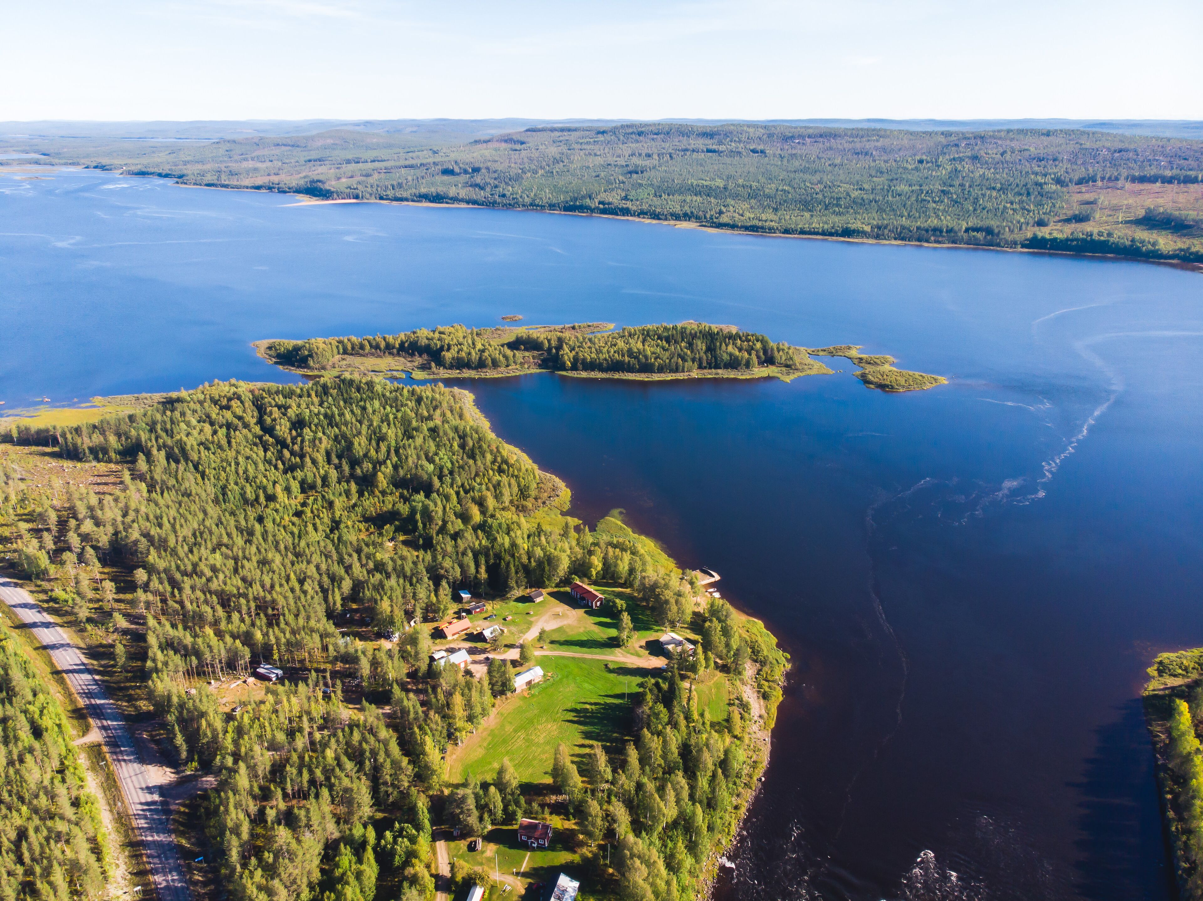 View of Kalix river, Kalixalven, Overkalix locality and the seat in Norrbotten county, Sweden, with forest in sunny summer day, aerial drone view