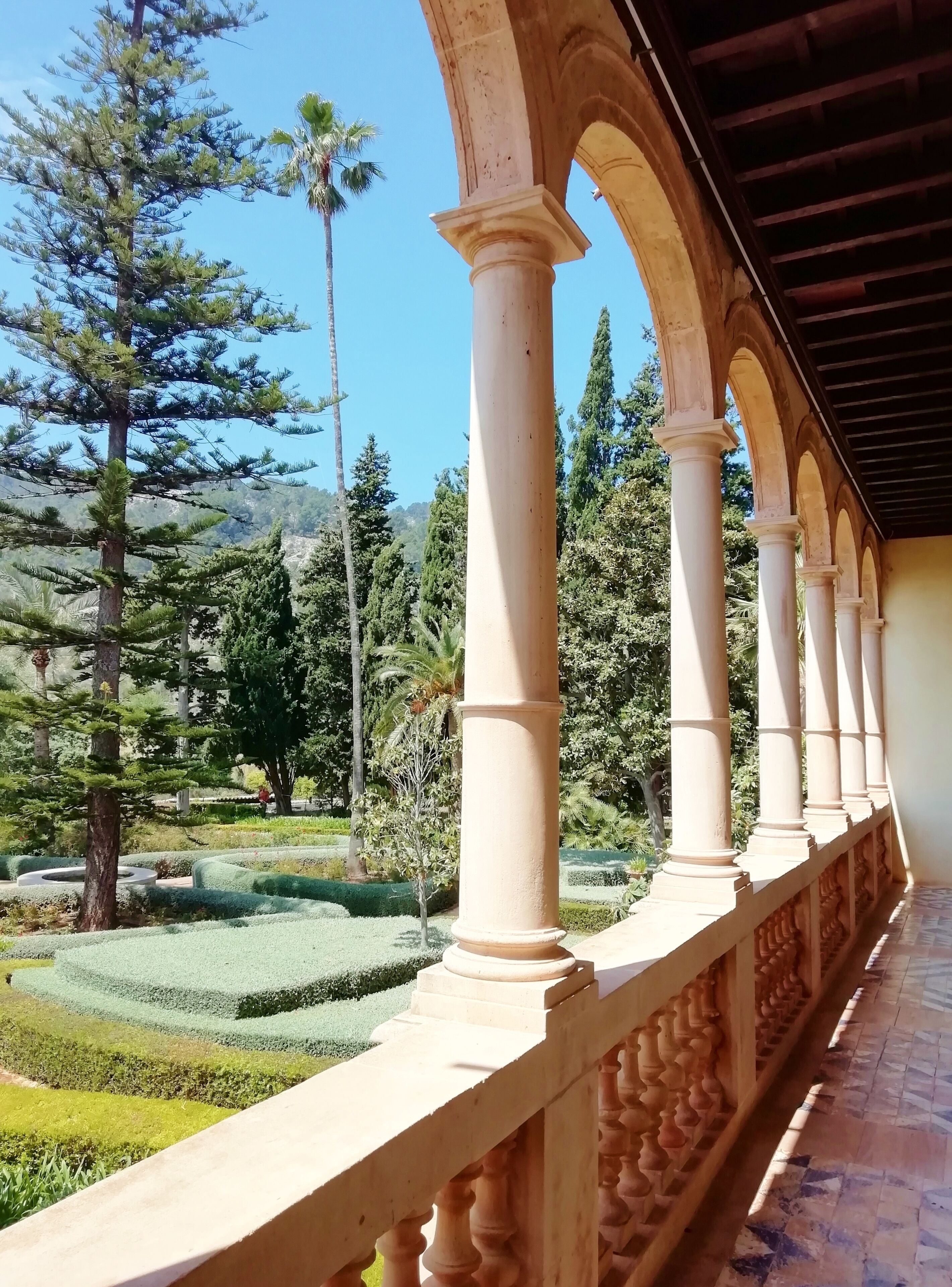 Un paseo cubierto con columnas y un jardín ajardinado.