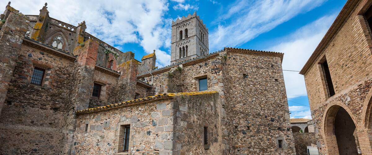 An old stone building with a tower, surrounded by other historic structures.