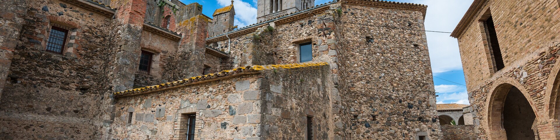 An old stone building with a tower, surrounded by other historic structures.