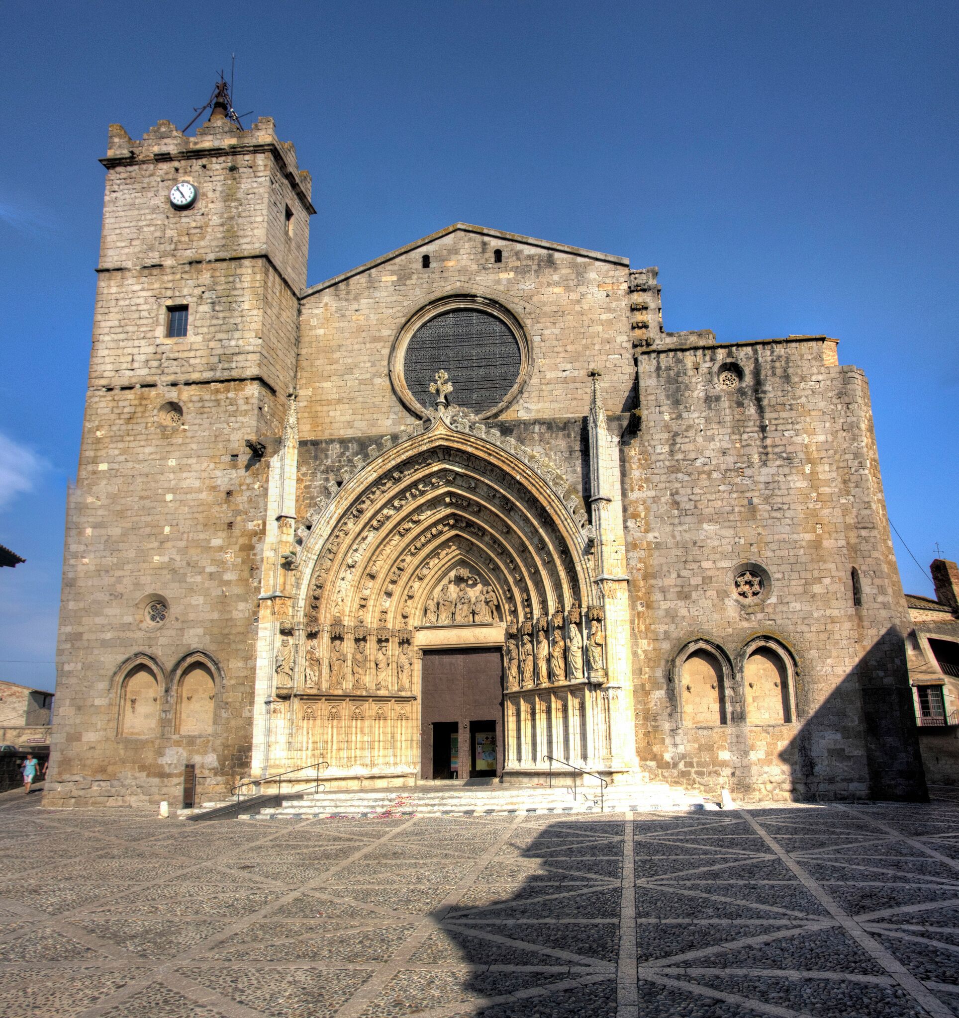 A historic cathedral with a large arched entrance, a clock tower, and detailed stone carvings.