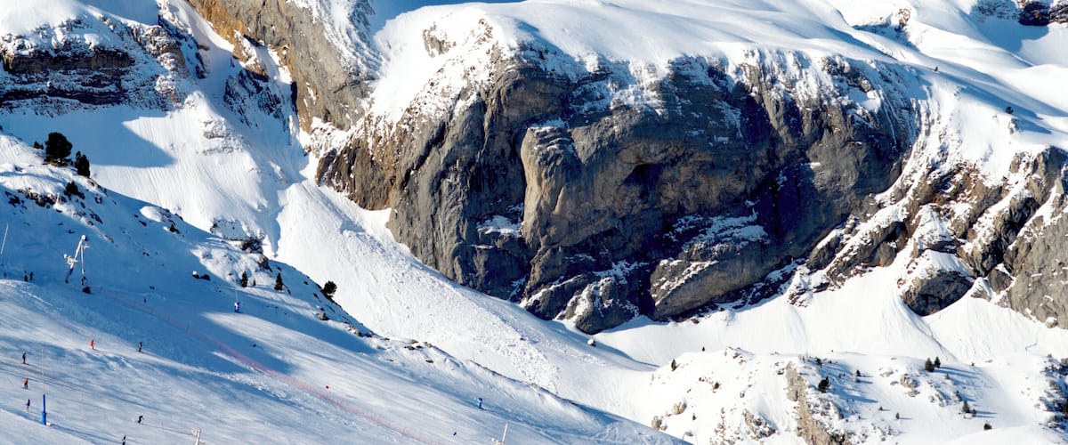 A snow-covered mountain with rocky outcrops and a clear blue sky.