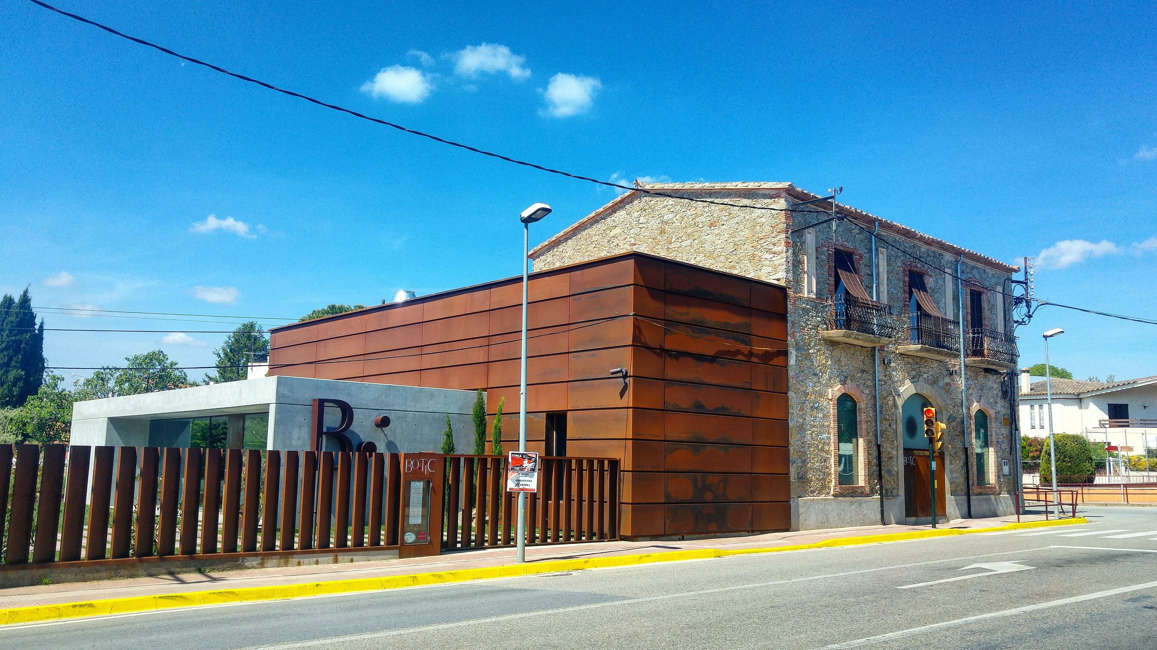 A building with a modern facade and a stone base, a metal fence, and a clear blue sky.
