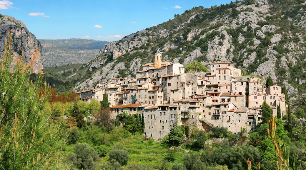 Un pueblo montañoso con edificios de piedra y una imponente torre de iglesia.