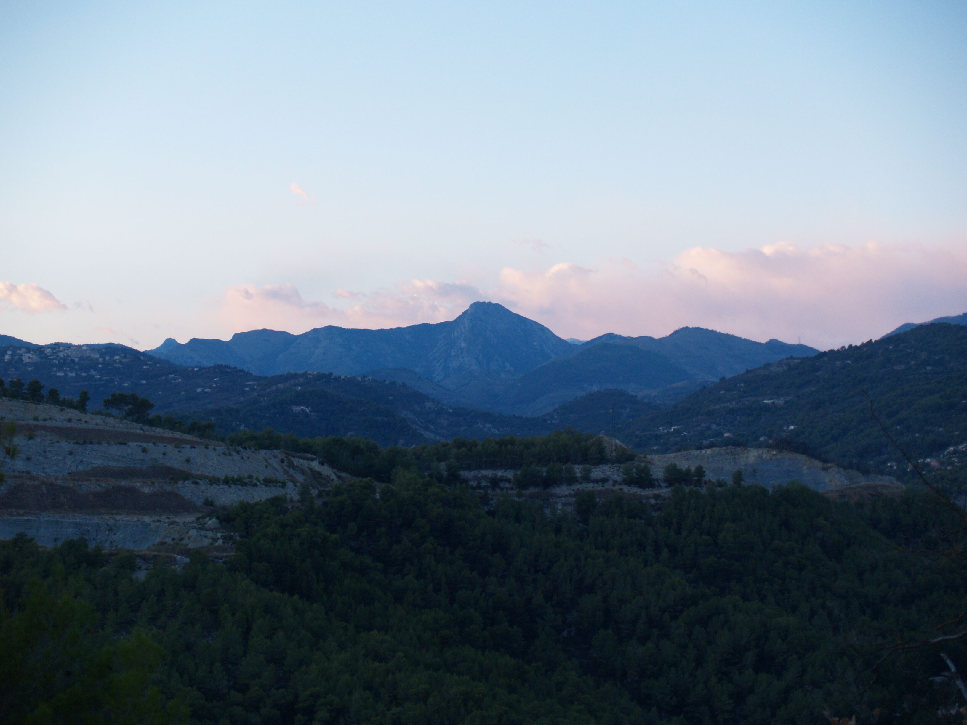 A mountainous landscape with dense forests and a clear sky.